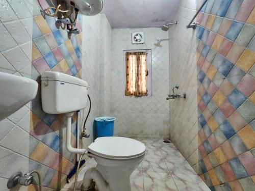uma casa de banho com um WC e uma parede em mosaico em Hotel Tirupati Regency Anandam em Shimla