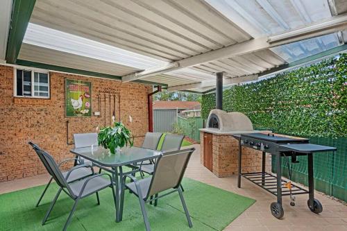 a patio with a table and chairs and a grill at Discover Mount Annan Spacious 6-BR House in Narellan