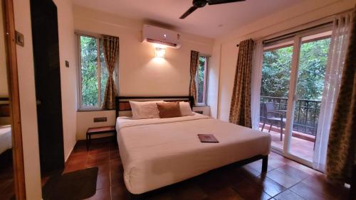 a bedroom with a bed and a balcony with windows at Forest Escapes Koyna in Koynanagar