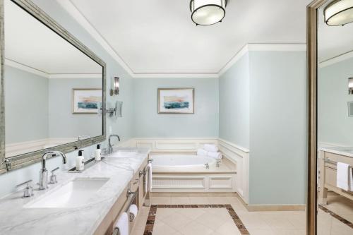 ein Badezimmer mit zwei Waschbecken, einer Badewanne und einem großen Spiegel in der Unterkunft The Ritz Carlton Key Biscayne, Miami in Miami