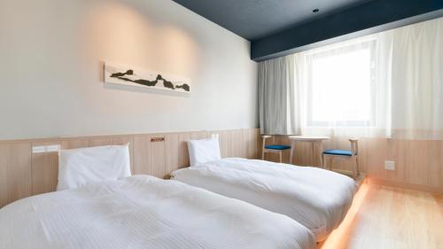 Vessel Hotel Campana Susukino في سابورو: غرفة نوم بسريرين بيض ونافذة