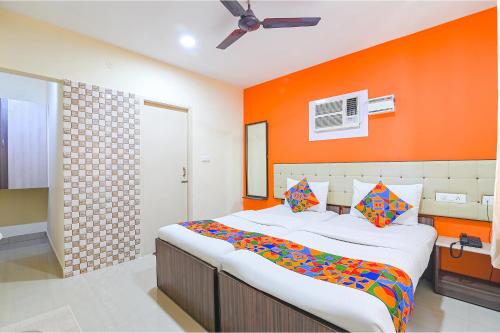 a bedroom with a large bed with an orange wall at FabHotel VRJ Residency in Chennai