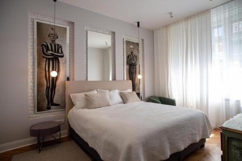 a bedroom with a white bed and two pictures on the wall at Pop's Apartments in Belgrade