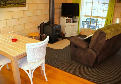 a living room with a table and a chair and a wood stove at Severn River Cottages in Severnlea