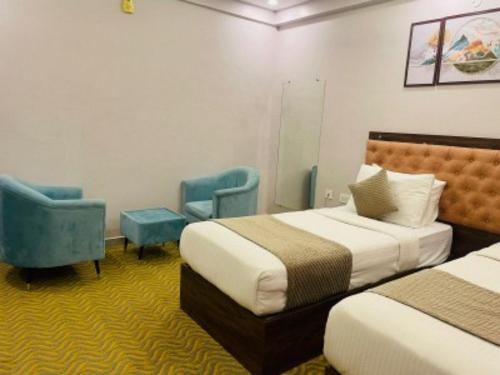 a hotel room with two beds and two chairs at VOVO HOTELS in Yelahanka