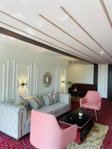 a living room with a couch and pink chairs at VOVO HOTELS in Yelahanka