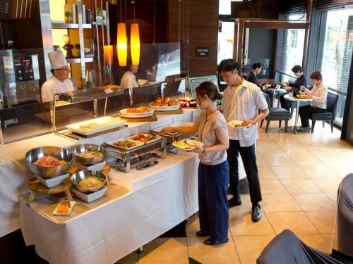 un grupo de personas de pie en un restaurante preparando comida en Hotel Hillarys en Osaka