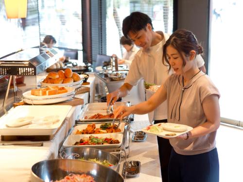 a man and a woman preparing food in a kitchen at Hotel Hillarys in Osaka
