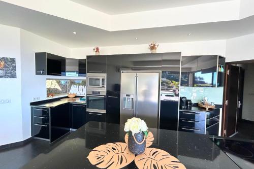 a kitchen with black cabinets and a vase of flowers on a table at Villa Tiki - wonderfull sea view in Punaauia