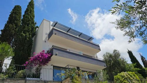 a white building with a balcony and purple flowers at Residence Alpha Apartments in Cavtat
