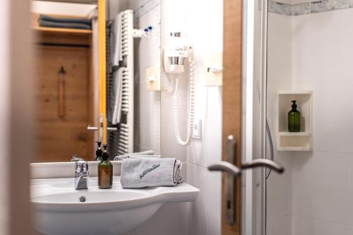 a white bathroom with a sink and a mirror at Hotel-Garni Schernthaner in Sankt Gilgen