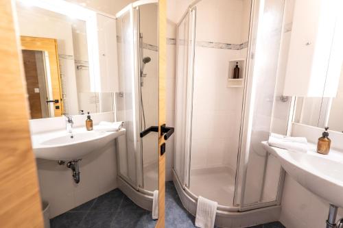 a bathroom with two sinks and a shower at Hotel-Garni Schernthaner in Sankt Gilgen