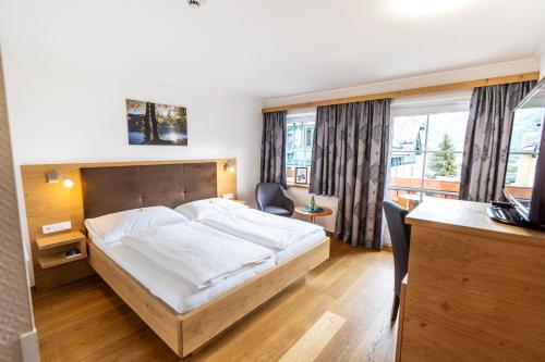 een slaapkamer met een bed, een bureau en een televisie bij Hotel-Garni Schernthaner in Sankt Gilgen