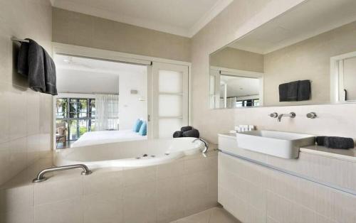 a bathroom with a tub and a sink and a bed at Mangrove Hotel in Broome