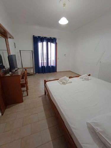 a bedroom with a large white bed and a desk at Nisaki chios apartments in Agia Ermioni