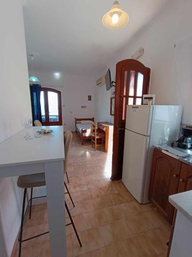 a kitchen with a white refrigerator and a table and chairs at Nisaki chios apartments in Agia Ermioni