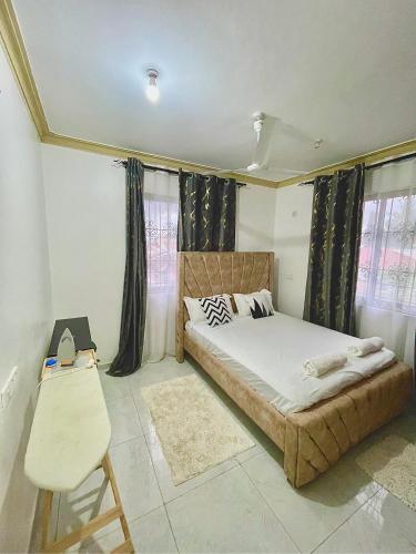 a bedroom with a bed and a chair and windows at Ngoki’s comfort apartment in Mombasa
