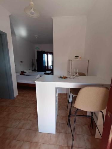 Agia ErmioniにあるNisaki chios apartmentsのキッチン(白いカウンター、椅子付)