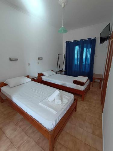 two beds in a room with blue curtains at Nisaki chios apartments in Agia Ermioni