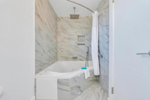 a bathroom with a tub and a shower with marble walls at The Ocean Resort Inn in Montauk