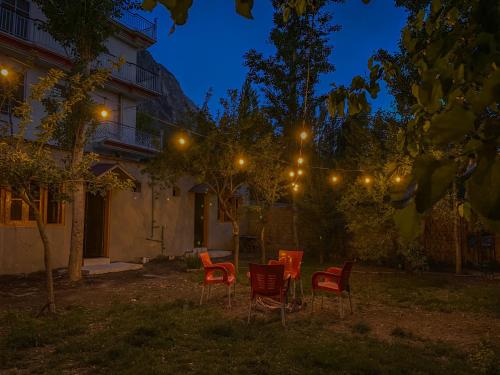 un groupe de chaises et de lumières dans une cour la nuit dans l'établissement Biafo House, à Skardu