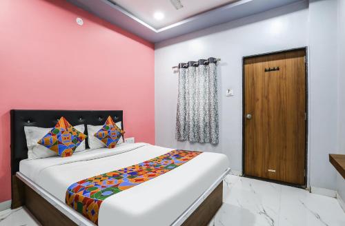 um quarto com uma cama e uma parede rosa em FabHotel Carnival I em Aurangabad