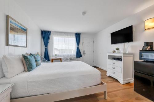a bedroom with a white bed and a flat screen tv at The Ocean Resort Inn in Montauk