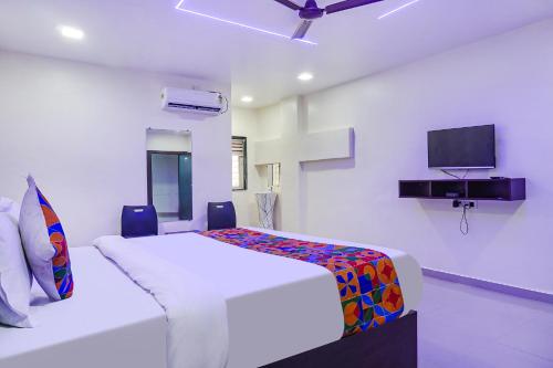 a white bedroom with a bed and a tv on the wall at FabHotel Atharva Executive in Pune