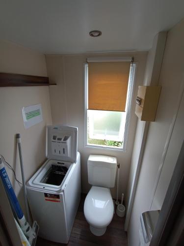 Elle comprend une petite salle de bains pourvue de toilettes et d'une fenêtre. dans l'établissement Mobil home l'oliverie, à Valras-Plage