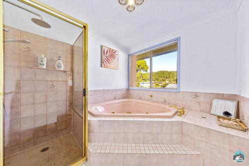 uma casa de banho com uma banheira e um chuveiro com uma janela em Aircabin - Woy Woy - Water Front - 6 Beds Lux Home em Daleys Point