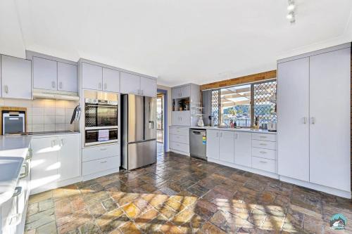 a kitchen with white cabinets and stainless steel appliances at Aircabin - Woy Woy - Water Front - 6 Beds Lux Home in Daleys Point