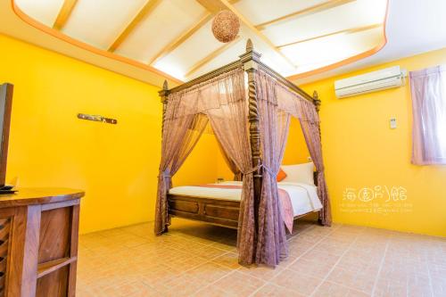 a bedroom with a canopy bed in a yellow room at Hai Yuan Bungalow II in Kenting