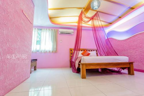 a bedroom with pink walls and a bed with a canopy at Hai Yuan Bungalow II in Kenting