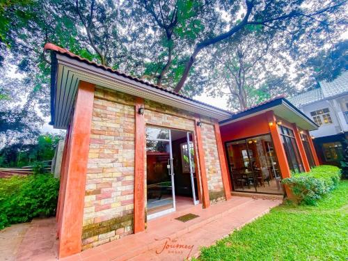 a brick building with glass doors in a yard at The Journey House Lifestyle Boutique Hotel in Kanchanaburi