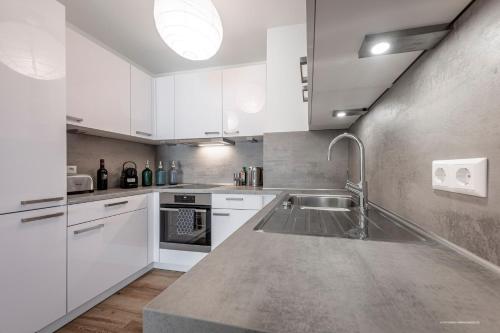 a kitchen with white cabinets and a stainless steel sink at Artdesign - 8 Pers - nähe Speyer Mannheim Heidelberg in Hockenheim