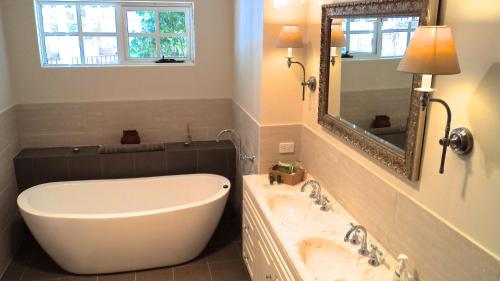 ein Badezimmer mit einer Badewanne, einem Waschbecken und einem Spiegel in der Unterkunft Lanterns Retreats in Dunsborough