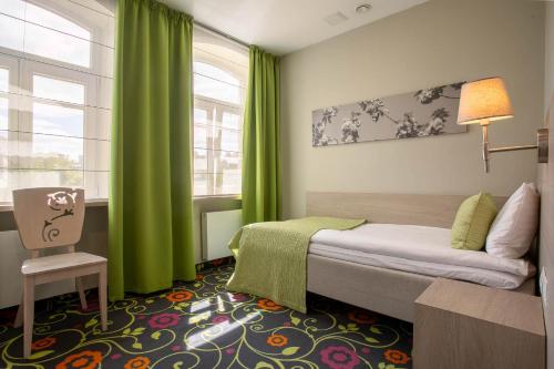 a bedroom with a bed with green curtains and a window at City Hotels Rūdninkai in Vilnius