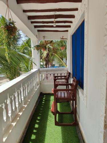 a balcony with chairs and a green floor at Barizieum Nest 1BR, Diani in Kwale