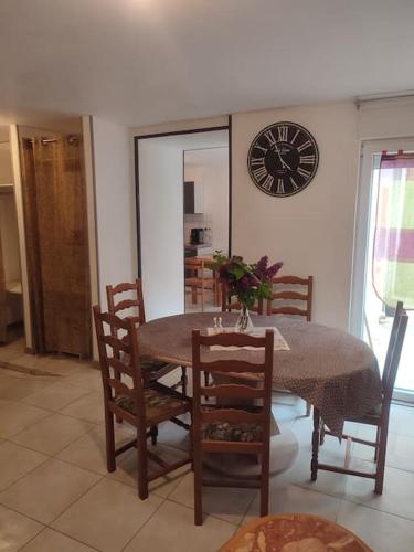 a dining room with a table and chairs and a clock at Gite 2 chambres avec cours in Weyer