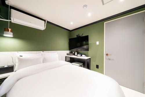 ein Schlafzimmer mit einem weißen Bett und einer grünen Wand in der Unterkunft Hotel May Yongsan in Seoul