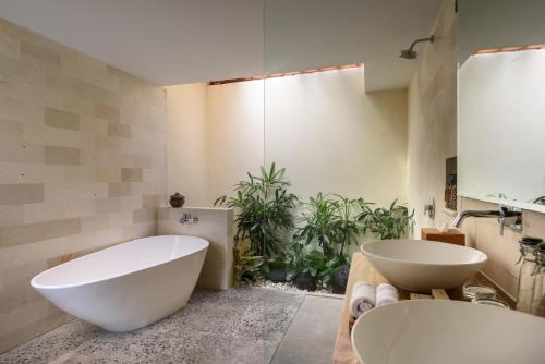 a bathroom with a large white tub and a sink at Anandathu Villas in Mengwi