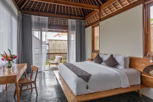 a bedroom with a large bed and a desk and a table at Anandathu Villas in Mengwi