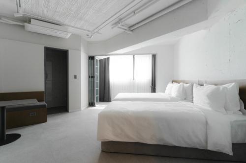 a white bedroom with a large bed and a desk at Homes Stay G-Valley Gasan in Seoul