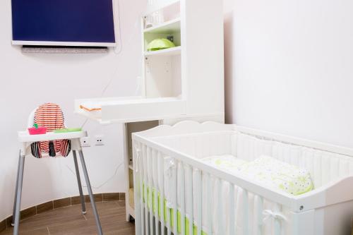 a white nursery with a crib and a sink at WH Apartments in Ljubljana