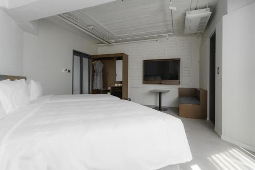 een slaapkamer met een groot wit bed en een flatscreen-tv bij Homes Stay G-Valley Gasan in Seoul