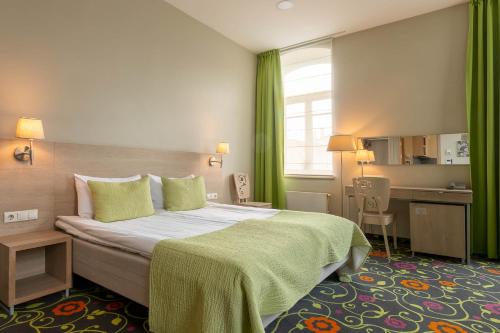 a hotel room with a large bed with green curtains at City Hotels Rūdninkai in Vilnius