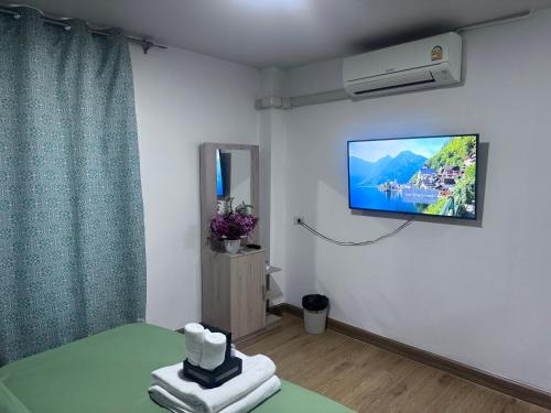 a room with a tv on the wall and a bed at Herb Hop House in Bangkok