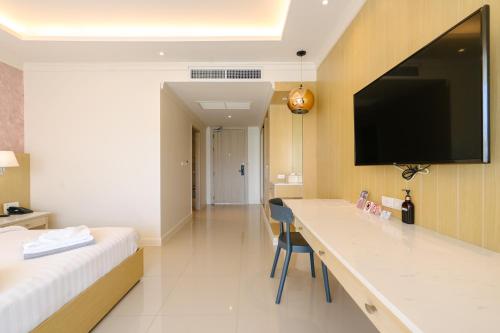 a hotel room with a bed and a desk with a flat screen tv at The Sea Cret Hua Hin in Hua Hin