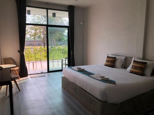 a bedroom with a large bed with a large window at หน้าวังมฤคทายวันรีสอร์ท in Ban Nong Khang
