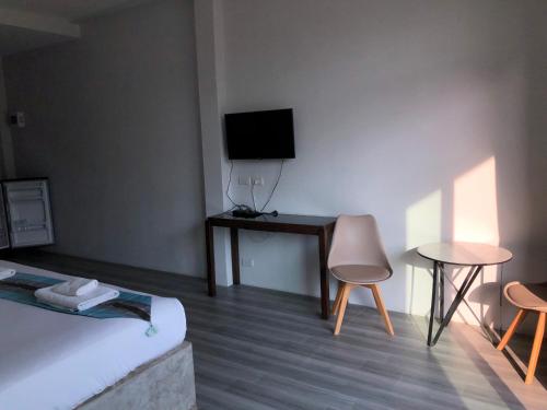 a room with a bed and a table and a television at หน้าวังมฤคทายวันรีสอร์ท in Ban Nong Khang
